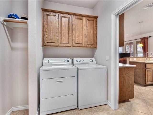 laundry area with sink, light tile patterned floors, cabinets, and washer and dryer