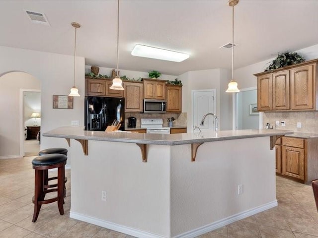 909 Big Thicket St, Georgetown, TX 78633 - kitchen featuring stainless steel microwave, black fridge, white range with electric stovetop, arched walkways, and tasteful backsplash