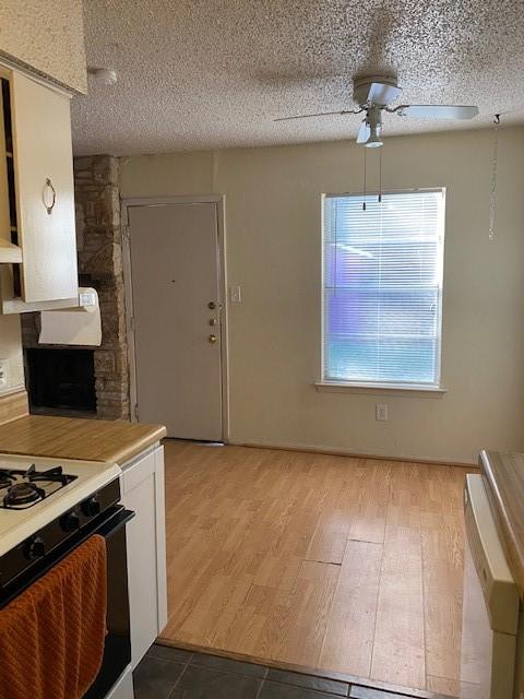 kitchen with range with gas cooktop, light hardwood / wood-style flooring, a textured ceiling, ceiling fan, and white cabinets