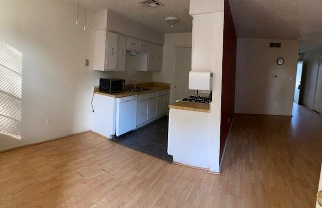 kitchen featuring white dishwasher, sink, wood-type flooring, and white cabinets