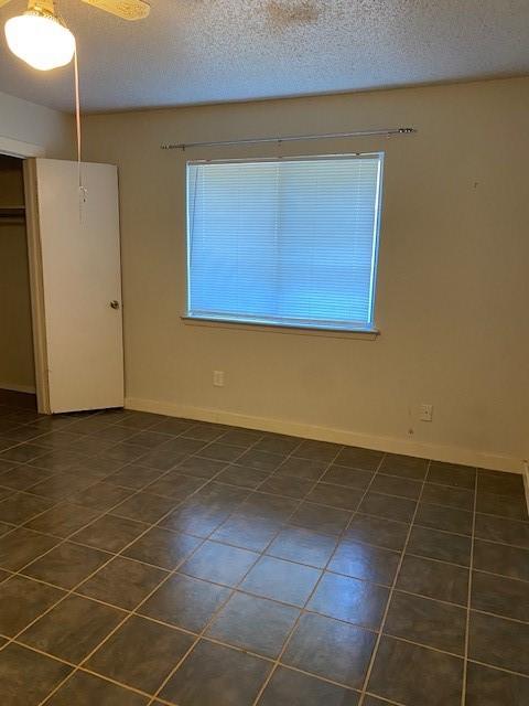 tiled empty room with a textured ceiling