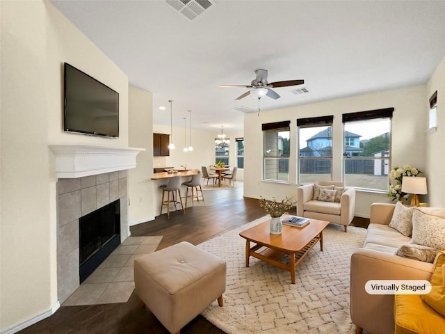 living room featuring ceiling fan with notable chandelier, a fireplace, and light wood-type flooring