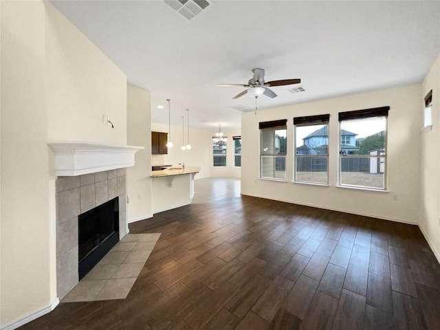 unfurnished living room featuring a fireplace, dark hardwood / wood-style floors, and ceiling fan with notable chandelier