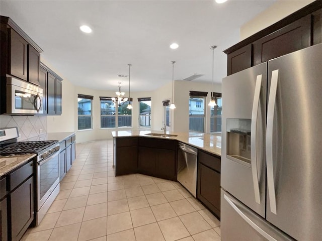 kitchen with dark brown cabinetry, stainless steel appliances, light stone countertops, and hanging light fixtures