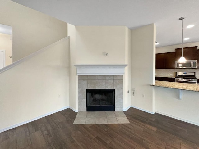 unfurnished living room with dark hardwood / wood-style flooring and a tiled fireplace