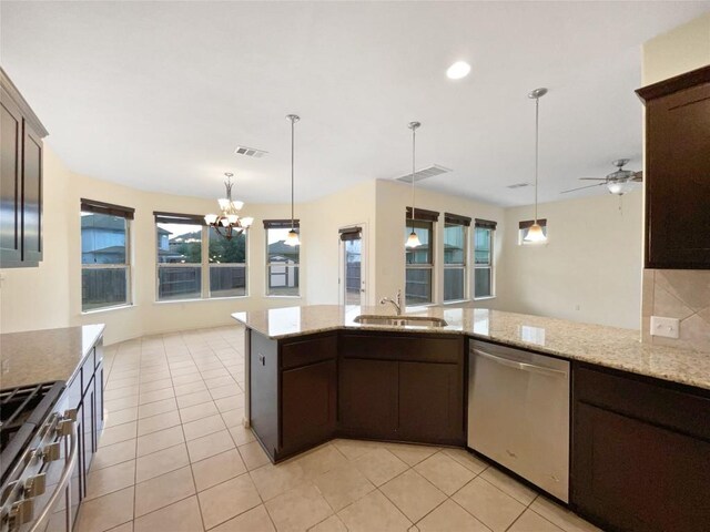 kitchen with appliances with stainless steel finishes, pendant lighting, sink, light stone counters, and dark brown cabinetry