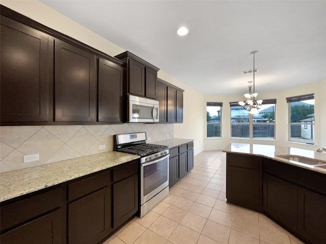 kitchen featuring dark brown cabinetry, decorative light fixtures, plenty of natural light, stainless steel appliances, and decorative backsplash