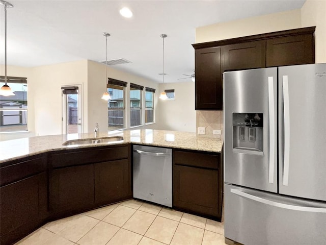 kitchen featuring sink, appliances with stainless steel finishes, hanging light fixtures, dark brown cabinetry, and tasteful backsplash