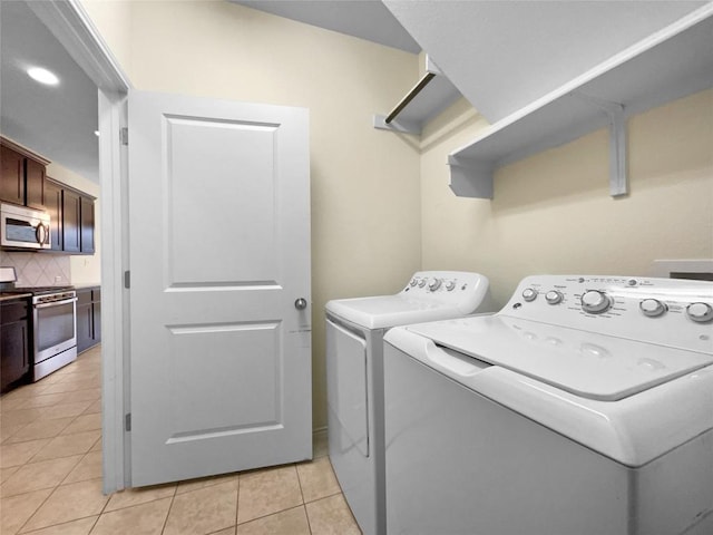 clothes washing area with washing machine and clothes dryer and light tile patterned floors