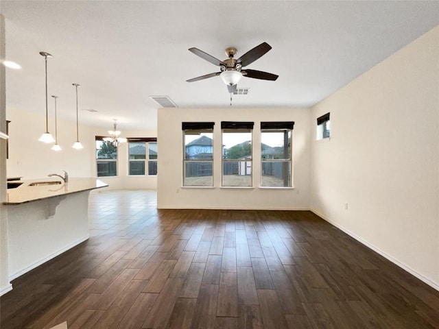 unfurnished living room with sink, ceiling fan with notable chandelier, and dark hardwood / wood-style floors