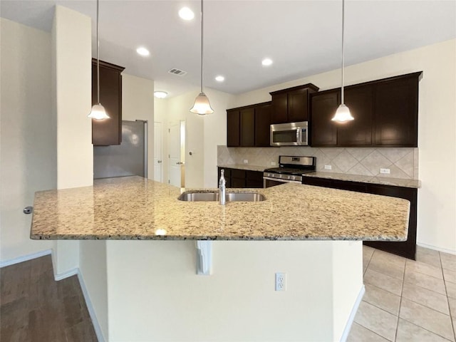 kitchen with stainless steel appliances, decorative light fixtures, kitchen peninsula, and sink