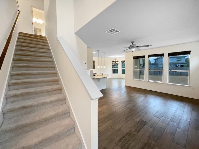 staircase featuring ceiling fan with notable chandelier and hardwood / wood-style floors