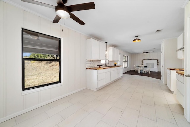 kitchen featuring butcher block counters, ceiling fan, sink, and white cabinets