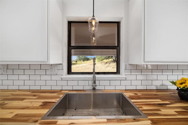 details with white cabinets, sink, wooden counters, and decorative light fixtures