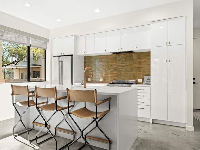 kitchen with white cabinetry, a breakfast bar area, and high end refrigerator