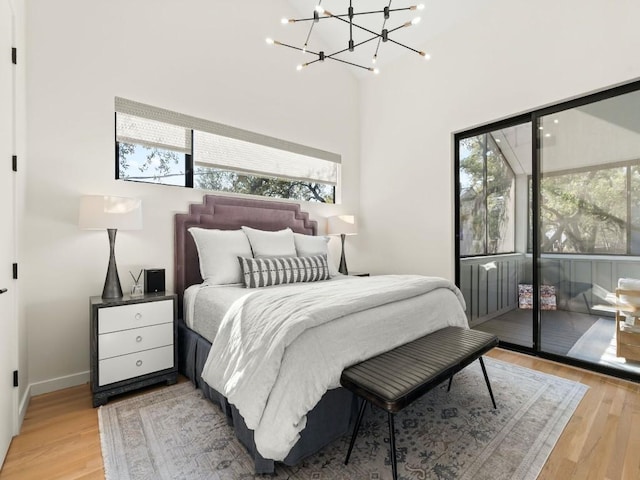 bedroom featuring wood-type flooring, access to exterior, and a notable chandelier