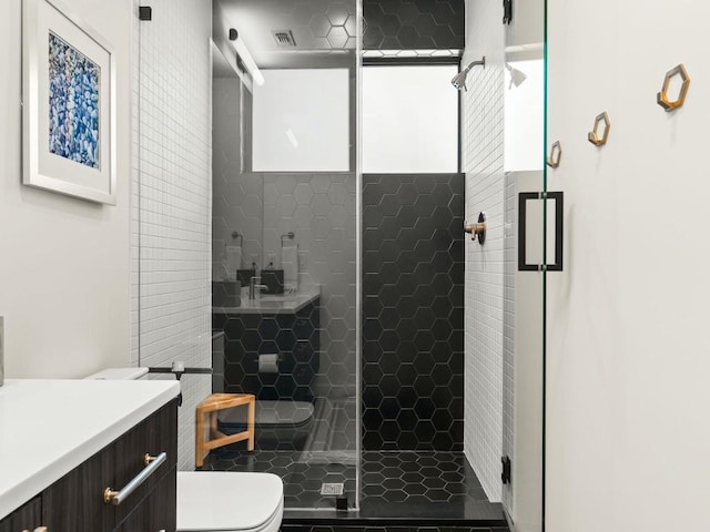 bathroom featuring vanity, a shower with shower door, and toilet