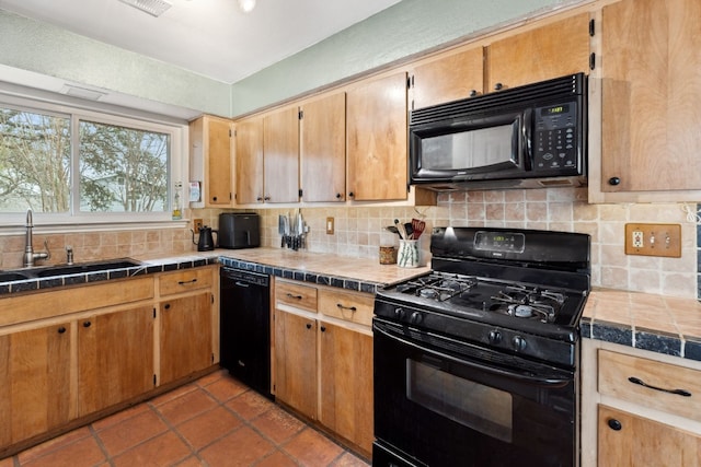 kitchen with sink, decorative backsplash, tile counters, light tile patterned floors, and black appliances