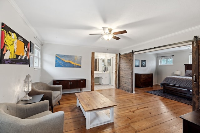 living room with crown molding, a barn door, and light wood-type flooring