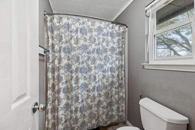 bathroom featuring walk in shower, a textured ceiling, and toilet