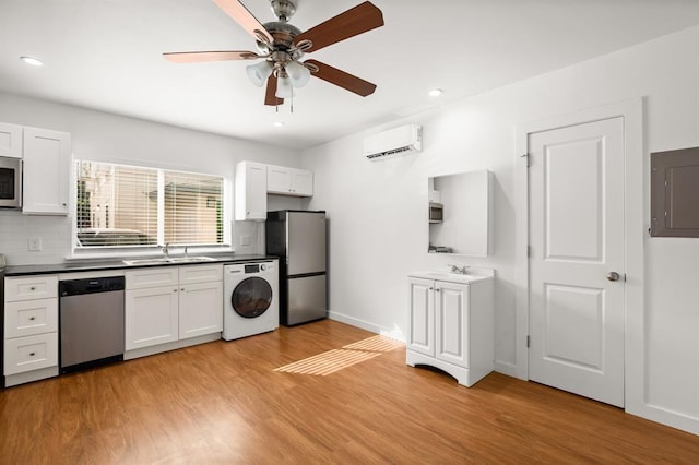 kitchen featuring washer / clothes dryer, white cabinetry, a wall unit AC, and stainless steel appliances