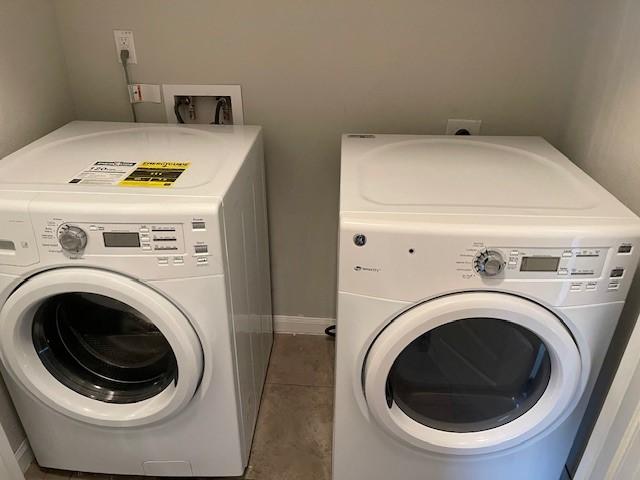 clothes washing area featuring washing machine and clothes dryer and tile patterned floors