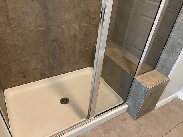 bathroom featuring an enclosed shower and tile patterned floors