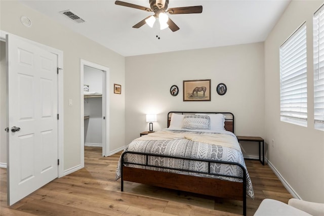 bedroom with baseboards, visible vents, a spacious closet, and light wood-type flooring