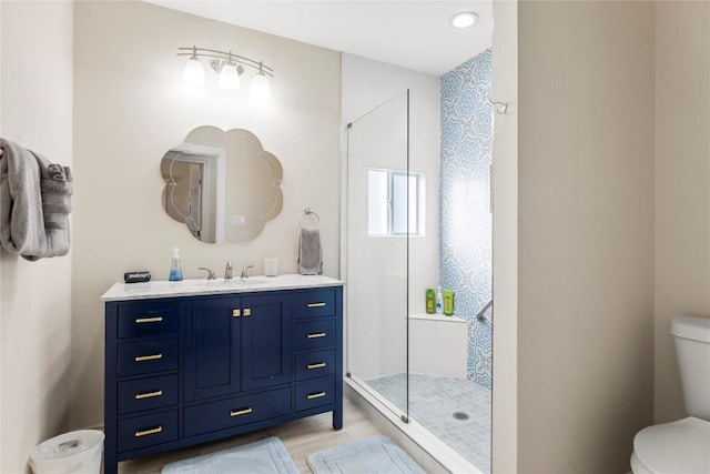 full bathroom with a tile shower, toilet, and vanity