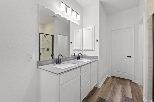 4829 Mozzafiato Ln, Round Rock, TX 78665 - bathroom featuring a shower stall, double vanity, and wood finished floors