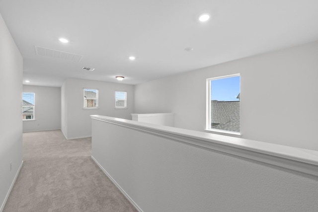 hallway featuring visible vents, a wealth of natural light, recessed lighting, and light colored carpet