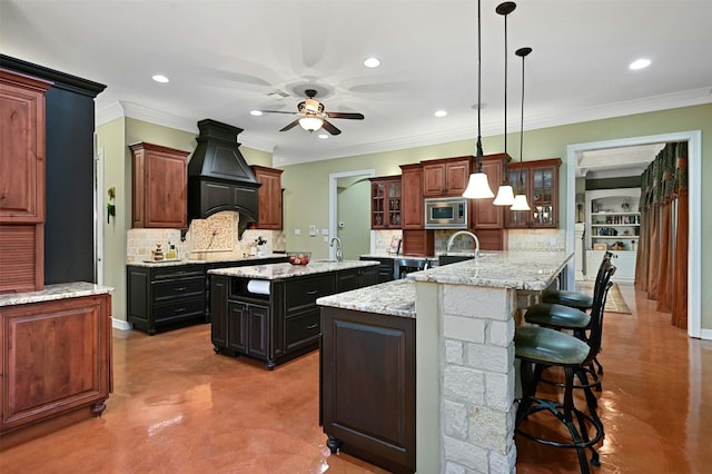 kitchen featuring pendant lighting, a large island, stainless steel microwave, and dark brown cabinets