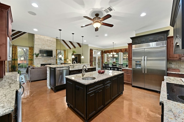 kitchen featuring stainless steel appliances, a center island with sink, dark brown cabinetry, and decorative light fixtures