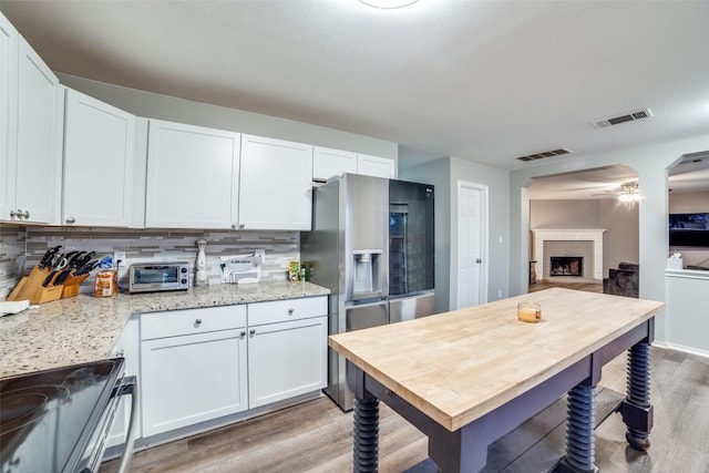 kitchen with light stone counters, appliances with stainless steel finishes, decorative backsplash, and white cabinets