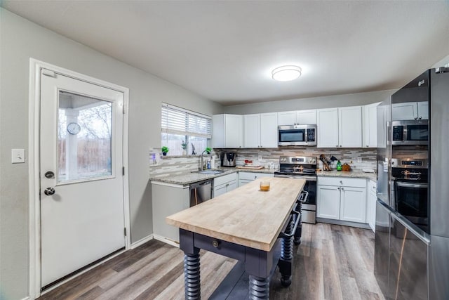 kitchen with tasteful backsplash, stainless steel appliances, sink, and white cabinets