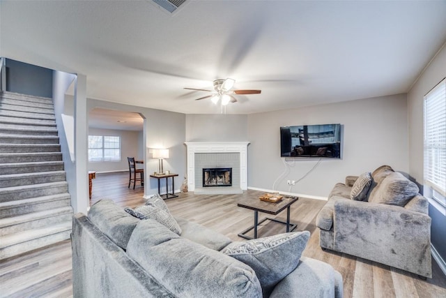 living room featuring wood-type flooring, ceiling fan, and a fireplace