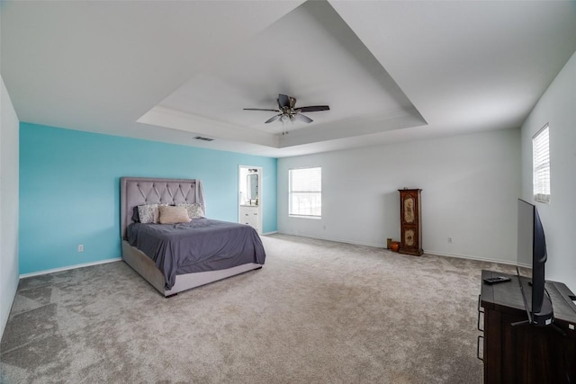 bedroom featuring multiple windows, a tray ceiling, and carpet flooring