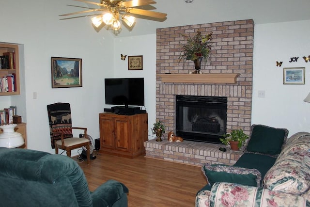 living room featuring hardwood / wood-style flooring, ceiling fan, and a brick fireplace