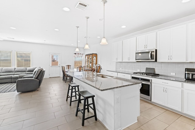 kitchen with decorative backsplash, a breakfast bar area, a sink, stone counters, and stainless steel appliances