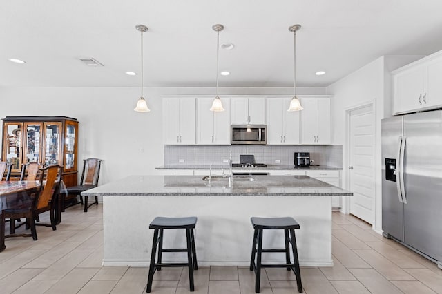 kitchen featuring a kitchen breakfast bar, stone countertops, appliances with stainless steel finishes, and decorative backsplash