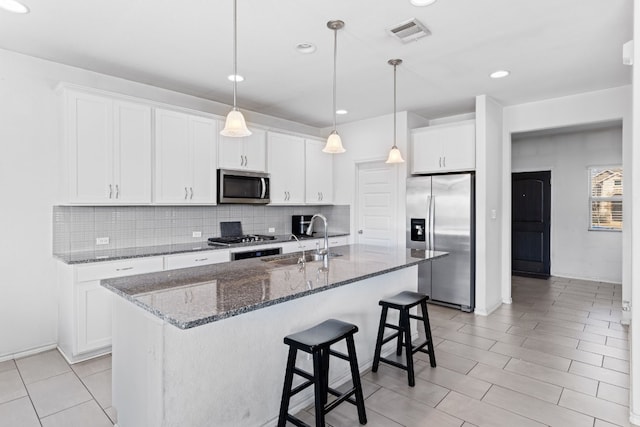 kitchen with a sink, stainless steel appliances, decorative backsplash, a kitchen bar, and visible vents