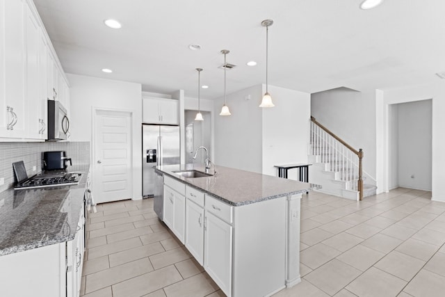 kitchen featuring visible vents, a sink, appliances with stainless steel finishes, white cabinets, and decorative backsplash