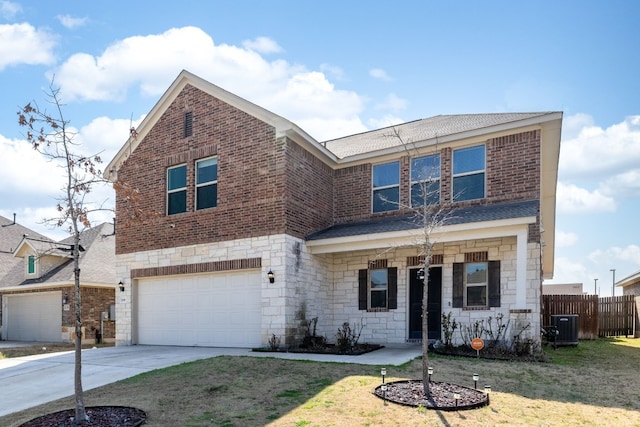 traditional home with fence, an attached garage, concrete driveway, stone siding, and central air condition unit