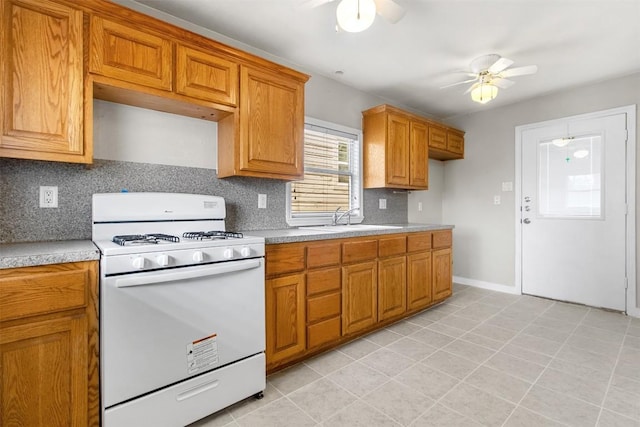 kitchen with sink, backsplash, light tile patterned floors, ceiling fan, and gas range gas stove