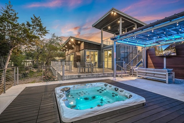 pool at dusk with outdoor lounge area and a deck