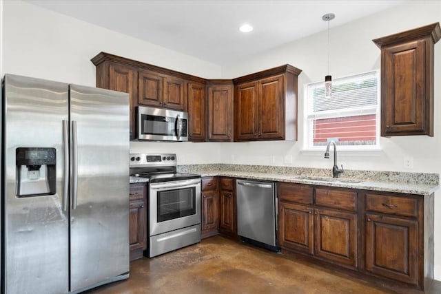 kitchen featuring stainless steel appliances, sink, light stone counters, and decorative light fixtures