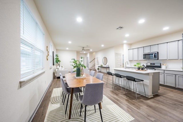 dining space with sink, light hardwood / wood-style flooring, and ceiling fan