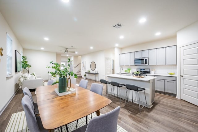 dining space with wood-type flooring, sink, and ceiling fan