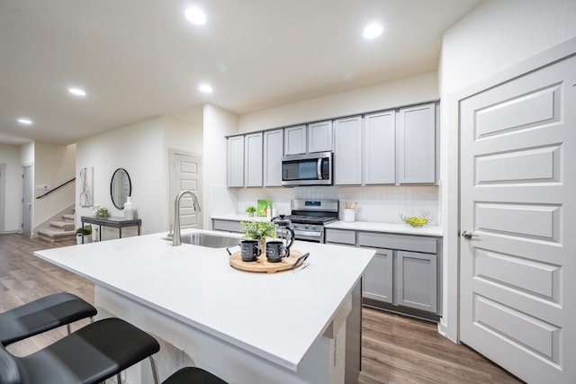 kitchen featuring gray cabinets, an island with sink, appliances with stainless steel finishes, and sink