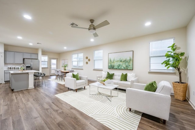 living room with ceiling fan, sink, and light wood-type flooring